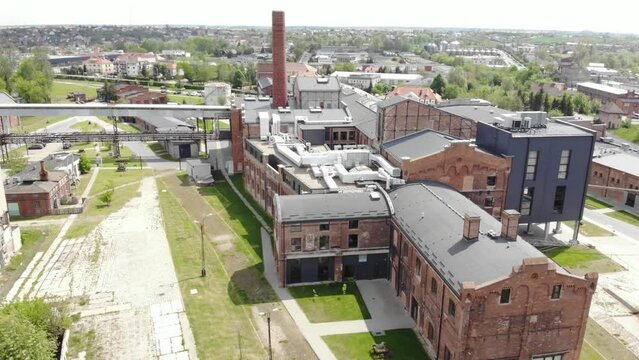 the chimney in Arche Hotel Żnin inside old sugar factory in Poland. The tall chimney of the factory is a famous landmark, rising above the surrounding landscape. Aerial orbit tilt up shot.