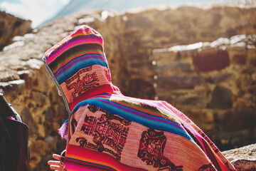 Traveler in poncho with backpack exploring ruins of Ollantaytambo Ruins in Sacred Valley of Peru. travel Concept