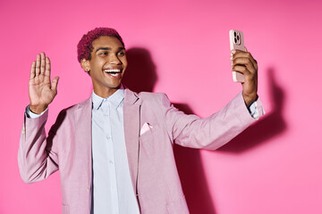 handsome young man posing unnaturally waving at mobile phone camera and smiling cheerfully