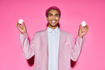 handsome young male model smiling unnaturally and holding delicious zefir in hands on pink backdrop