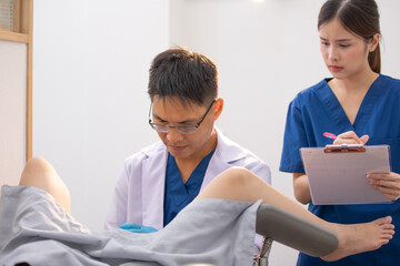 Asian doctor conducting a pelvic exam on a patient at hospital or in premium clinic. gynecological examination. Well-being of women concept - obrazy, fototapety, plakaty