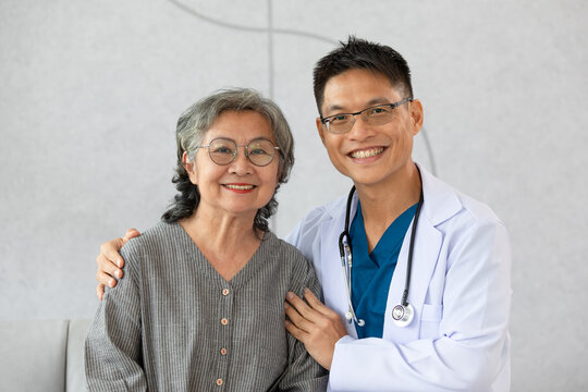 Happy doctor and elderly patient smile and looking camera nursing at home. Asian senior woman and doctor giving care and empathy to patient or retirement in homecare service. Elderly care concept