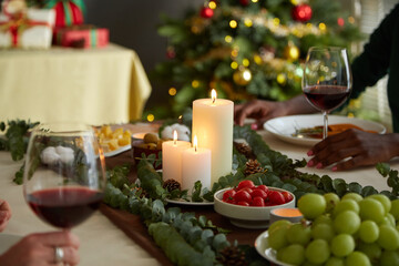 Burning candles on dinner table with various appetizers prepared for Christmas dinner