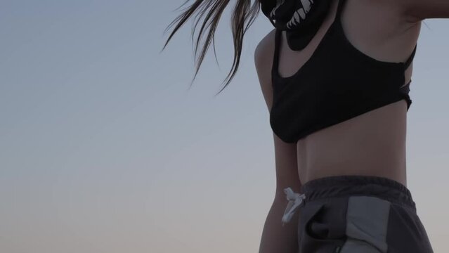 Young woman in sportswear standing on a buggy in desert sand against sunset background