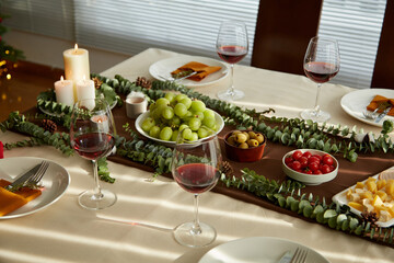 Decorated Christmas dinner table with appetizers and glasses of wine