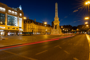 Night traffic in the city of Lisbon with the Obelisk Monument to the Restorers on Restauradores square in the background, Lisbon, Portugal