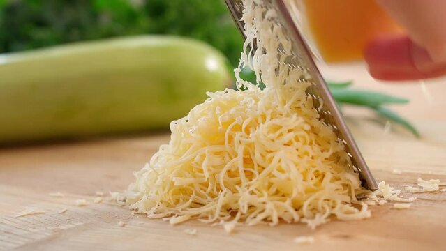 Cheese is grated on a wooden board using a fine grater. Close-up