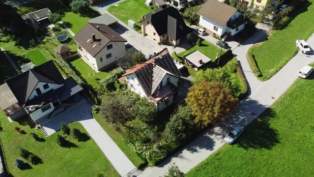 Workers replace tiling and shingles on slanted roof in middle of quiet neighborhood