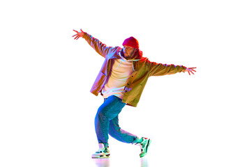Sportive, stylish young man in sportswear dancing street style dance isolated over white studio background in neon light. Concept of contemporary dance, street style, fashion, hobby, youth. Ad