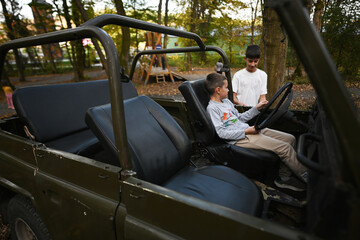 Two brothers in convertible car in autumn forest.