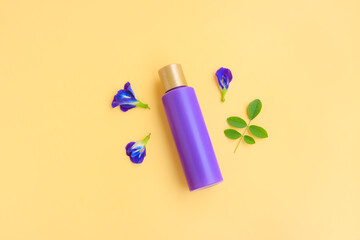 Purple cosmetic bottle with Butterfly pea flower and Green leaves on yellow background, Plastic bottle 