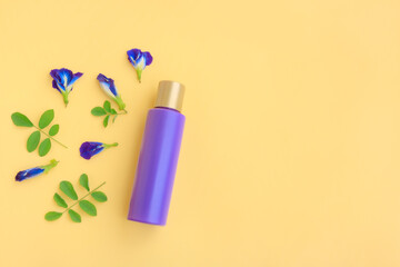 Purple cosmetic bottle with Butterfly pea flower and Green leaves on yellow background, Plastic bottle 