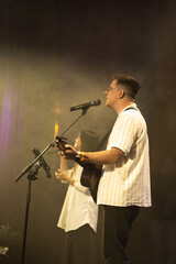 A duet of singers is performing a song on stage. Worship band sings and worships God in the church. Church service.