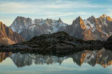 Silhouette of Hiker, Mountains and Reflection in Lac Blanc Lake at Sunset. Golden Hour. French Alps, France