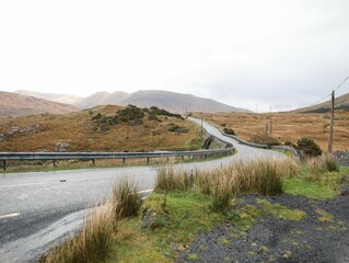 Obraz premium a curvy street with a grassy landscape, and a highway below the hill