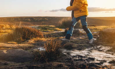 Energetic woman walking in waterproof hiking boots along trekking path with frozen puddleson on cold early winter morning