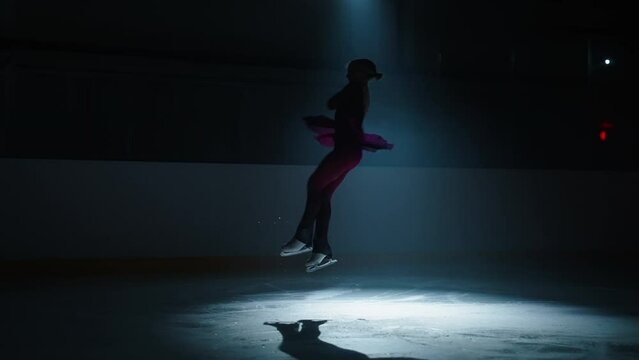 Woman Figure Skater Training Jumps On Ice Rink, Falling On Ice, Silhouette In Darkness