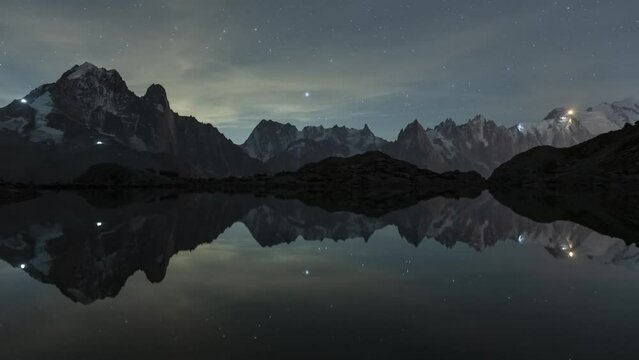 Starry Sky over Mountains and Reflection in Lac Blanc Lake. Night Landscape. Aiguilles Rouges, French Alps, France. Time Lapse