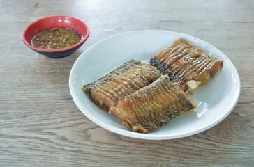 crispy fried chop large head hair tail fish arranging on plate dipping spicy chili sauce in cup   