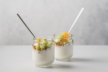 Kiwi granola yogurt in glasses on white background with copy space