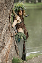 Fototapeta na wymiar A pretty young faun in the woods. Mythological forest creature at the tree