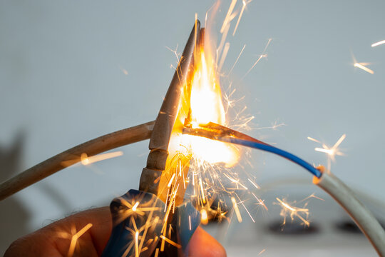 flame and sparks with pliers cutting  electrical cables, fire hazard concept, soft focus close up