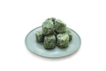 Frozen spinach cubes portion on a ceramic plate, isolated on white