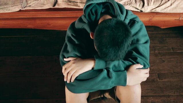 Asian kid boy Upset, sitting in the dark, thinking about conflicts, family relationships. sad face, Unhappy child sitting with head down, Emotion sad and sad face, depression children concept