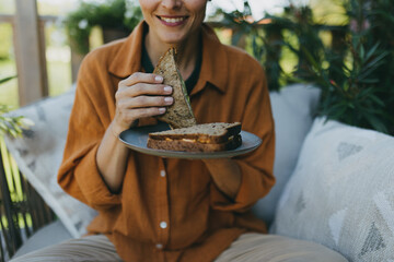 Beautiful woman relaxing in the garden, eating sandwich. Mother having moment to herself while her...