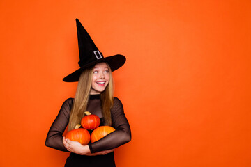Photo portrait of pretty blonde teenager girl pumpkins look empty space dressed black halloween outfit isolated on orange color background