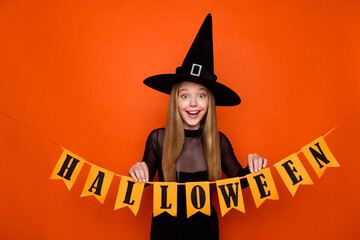 Photo of impressed funky lady wear black wizard costume cap hanging halloween flags isolated orange color background