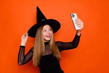 Photo of attractive blonde teen woman take selfie photo streaming dressed black halloween clothes isolated on orange color background
