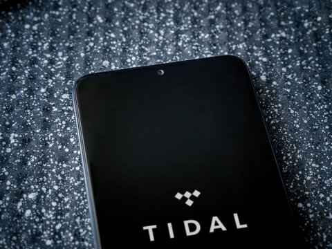Lod, Israel - July 16,2023: TIDAL Music app launch screen on smartphone on metallic background. Close up top view flat lay.