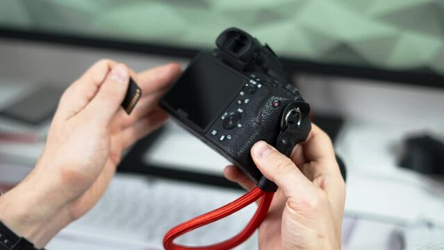 A man inserts a memory card into a photo camera. Close-up of hands and equipment.