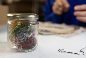 Colorful threads close up and a woman background embroidering by hand