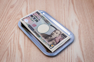 Japanese 10,000 yen bills are placed in change trays for businesses and purchases.