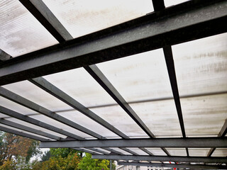 large metal pergola with galvanized surface structure. glass windows will replace Plexiglas. parked...