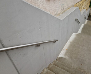 a staircase with concrete sides at a public building. the safe staircase has two handrails, one...