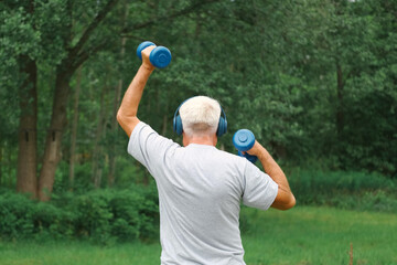 Senior man working out outdoors. Person lifting dumbbells. Old male exercising at park. Healthy people lifestyle. Active sport training. Older elderly sportsman doing fitness exercise. Workout session