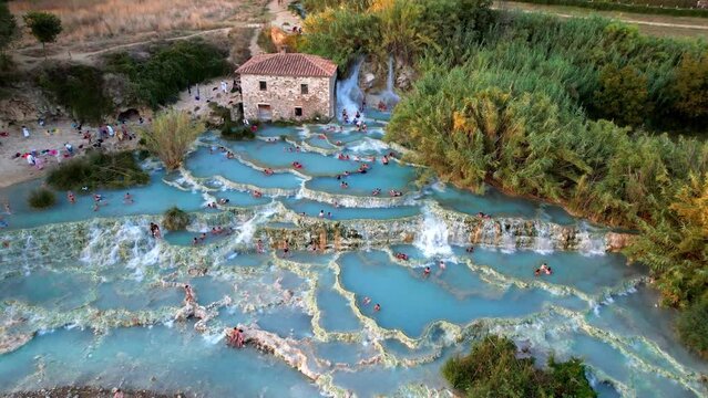 Aerial 4K view of Saturnia thermal hot springs. Scenic cascades of Mulino vecchio (Terme di Saturnia) in Tuscany, Italy. Natural geothermal pools at sunset