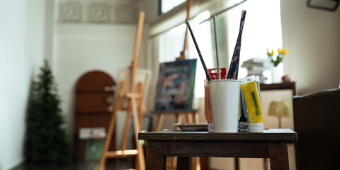 Unique artist workspace interior with bookcase, artworks, painting accessories, decoration and elegant personal stuff. Modern work room for artist.