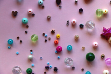 Various colorful beads on bright pink background. Top view.