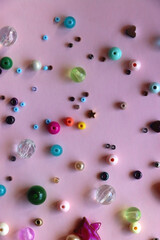 Various colorful beads on bright pink background. Top view.