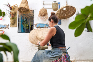 Rear view of Hispanic woman weaving a basket with esparto fibers. Manual work, tradition and...