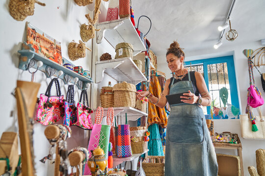 Female Hispanic souvenir shop owner taking inventory with digital tablet