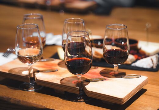 Dinner, wine tasting at old winery. Elegant wine pairing glasses filled with red, white, rose selections on rustic wooden table. Guests enjoy conversation in warm setting. Agrotourism, vineyard event