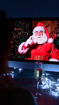 Woman talking to santa claus by video call on computer on new year's eve. Vertical video.