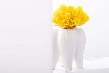 А bouquet of yellow Crocus flowers in white ceramic vase isolated on white background.