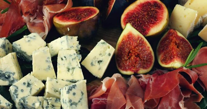 Figs, jamon, spinach leaves and blue cheeses on a wooden board. Snacks set.