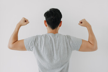Backside view of Asian man back wear grey t-shirt raising arms, showing muscles biceps power,...